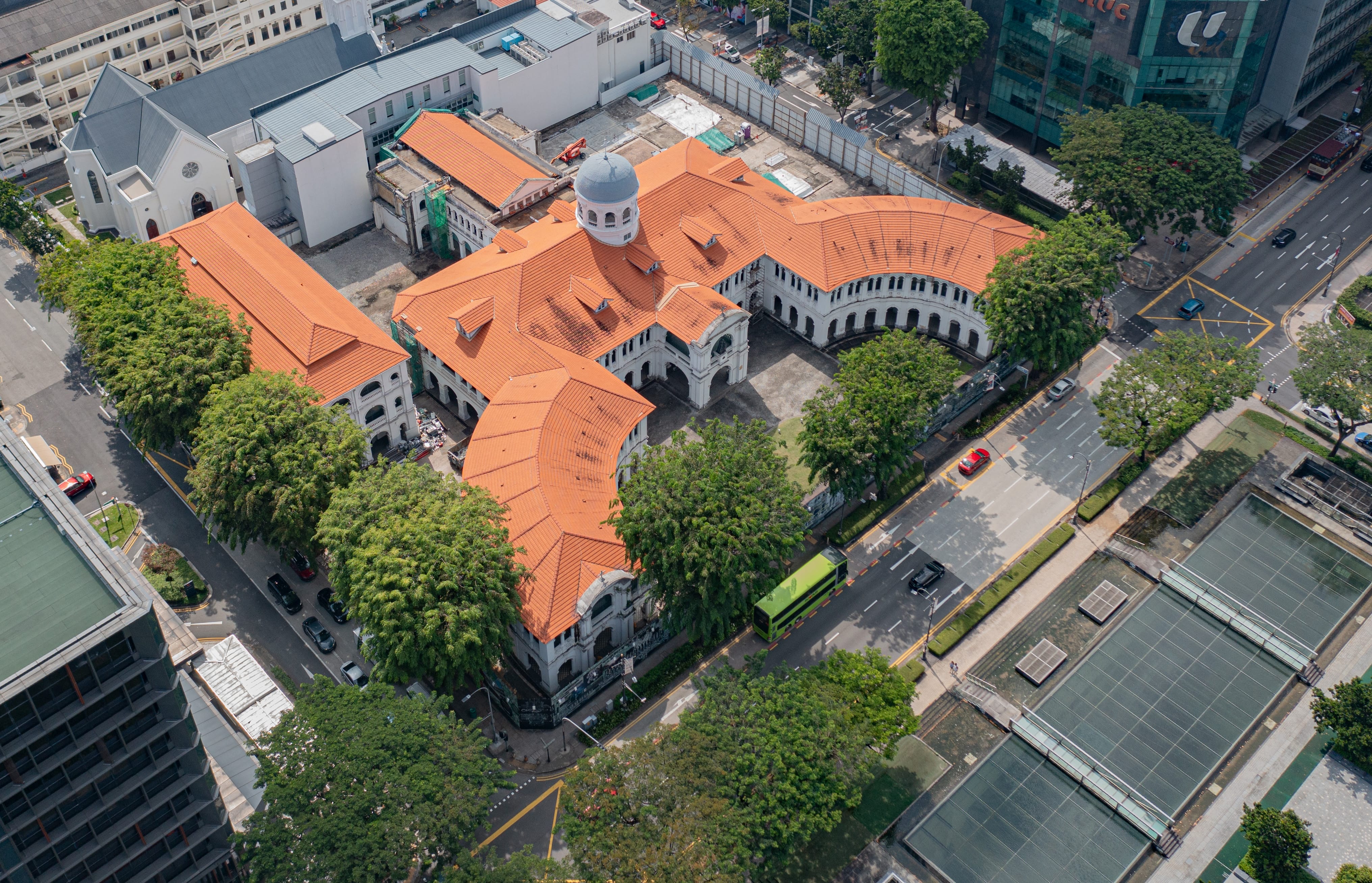 Aerial view of the Asian Civilisations Museum in Singapore, with orange tiled roofs and white facades, surrounded by greenery and city streets.